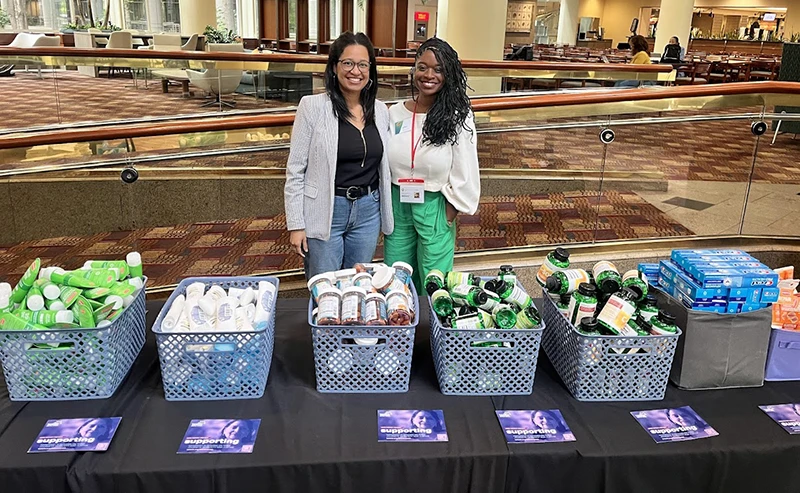 Two women standing in front of a table with personal care products and Tahirih informational materials