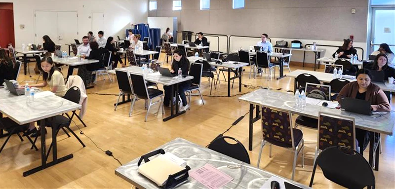 Legal professionals working at desks in a large gymnasium like room.